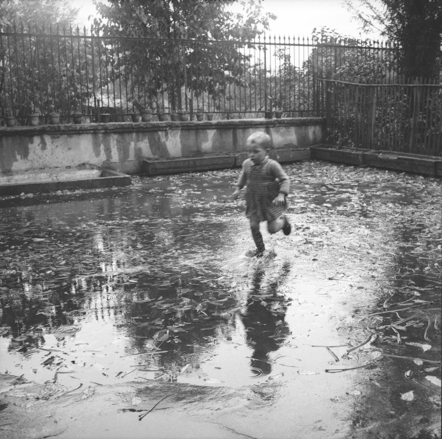 [Enfant courant dans les flaques d'eau de la cour de l'école]