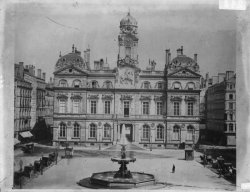 [Place des Terreaux et hôtel de ville de Lyon : fiacres et passants autour de la fontaine centrale]