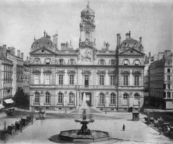 [Place des Terreaux et Hôtel de ville de Lyon : fiacres et passants autour de la fontaine centrale]